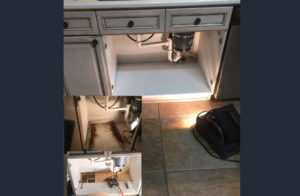Under-sink cabinet with plumbing and tools.