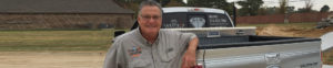 Man standing beside a pickup truck.