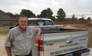 Smiling man beside a pickup truck.